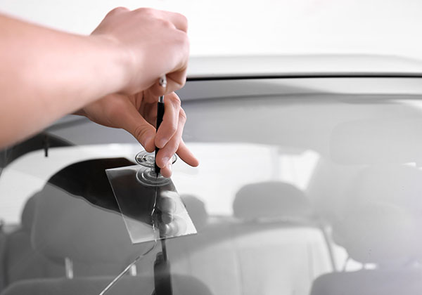 Technician fixing a crack in a car windshield